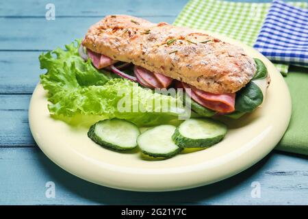 Piatto con gustoso sandwich di ciabatta su sfondo di legno colorato Foto Stock