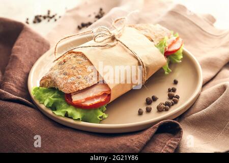 Piatto con gustoso sandwich di ciabatta sul tavolo Foto Stock