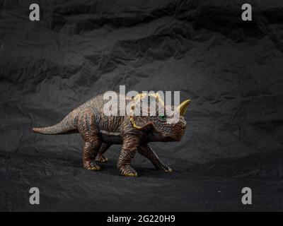 Piccolo modello in plastica di dinosauro giocattolo su sfondo scuro Foto Stock