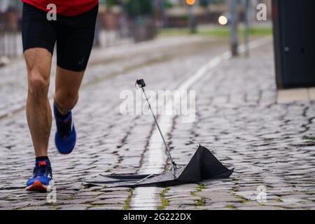 08 giugno 2021, Hessen, Francoforte sul meno: Uno jogger passa davanti a un ombrello rotto sulle rive del meno. Nel corso della giornata, è previsto un tempo variabile e docce inferiori. Foto: Andreas Arnold/dpa Foto Stock