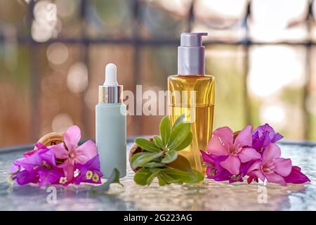 Surreale bouganvillea rosa brillante fiori in un cono gelato e mock up di bottiglie cosmetiche. Bottiglia cosmetica di olio e bottiglia di vetro a goccia. Estate prodotti di bellezza sfondo Foto Stock