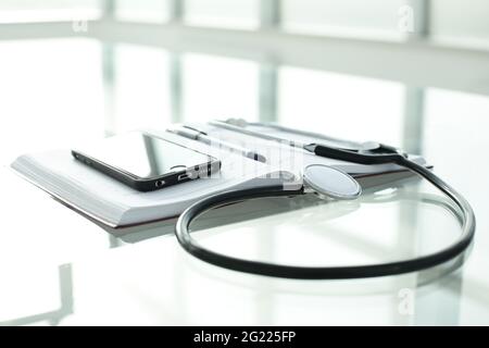 Telefono diario penna e stetoscopio su tavolo di vetro Foto Stock