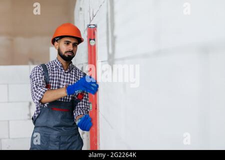 Mason controllo filo a piombo del muro di casa essendo realizzato da aerato autoclavato blocchi in calcestruzzo Foto Stock