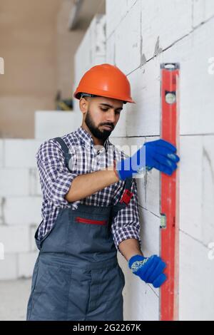 Mason controllo filo a piombo del muro di casa essendo realizzato da aerato autoclavato blocchi in calcestruzzo Foto Stock