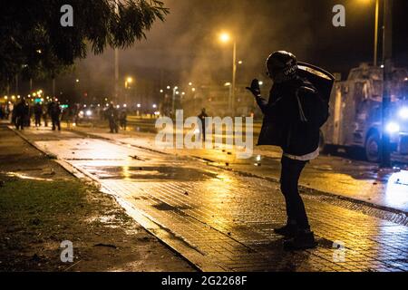 Un protestore della prima linea sfida la polizia durante la dimostrazione. Il 4 giugno, il governo colombiano ordinò ai dimostranti di smantellare il campo medico volontario, posto alla 'porta americana' ribattezzato 'porta di resistenza' a Bogot·. In risposta a ciò, le organizzazioni di diritto umano hanno chiesto al sindaco di Bogot· di dare loro un posto facoltativo per istituire il campo medico. Non hanno ottenuto una risposta e invece sono stati attaccati dalla polizia anti-sommossa durante la sera. I dimostranti sono stati sparati con barattoli di gas lacrimogeni, granate di stordimento e cannoni ad acqua. Il confronto durò più di Foto Stock