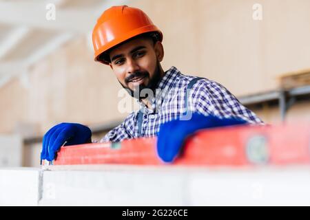 Mason controllo filo a piombo del muro di casa essendo realizzato da aerato autoclavato blocchi in calcestruzzo Foto Stock