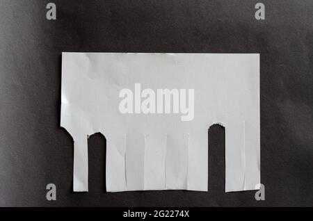 Foglio bianco vuoto con linguette a strappo su sfondo grigio. Foglio di carta sgualcito con strisce irregolari. Non tutti i segnalibri a strappo. Via A. Foto Stock