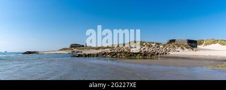 Vista panoramica di vecchi bunker sulle spiagge di Skagen, nel nord della Danimarca, con il faro sullo sfondo Foto Stock