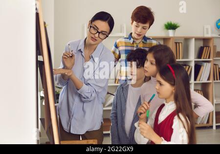 Insegnante a bordo che spiega la lezione soggetto a bambini studenti vista laterale shot Foto Stock