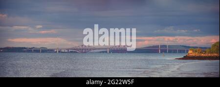 Panorama di tre ponti contro il cielo tramonto. Firth of Forth. Forth Bridges e Queensferry Crossing, Scozia, Regno Unito Foto Stock