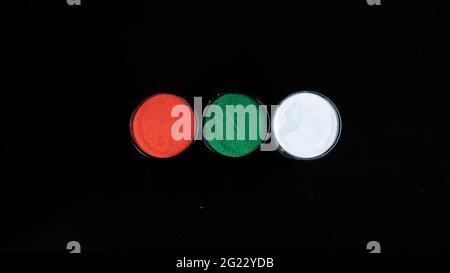 Vista dall'alto di tre colori riempiti di vetro isolati su sfondo nero (zafferano, verde e bianco) Foto Stock