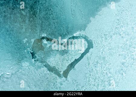 Struttura del ghiaccio sulla finestra. Iscrizione cuore su vetro congelato. Colore gradiente verde. Concetto di giorno e amore di San Valentino Foto Stock