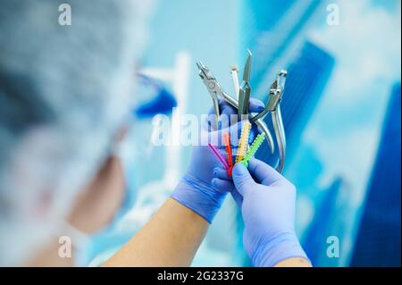 Dentista femminile non riconoscibile in indumenti da lavoro protettivi che tengono utensili dentali in acciaio inox per esame orale e trattamento dentale. Foto Stock