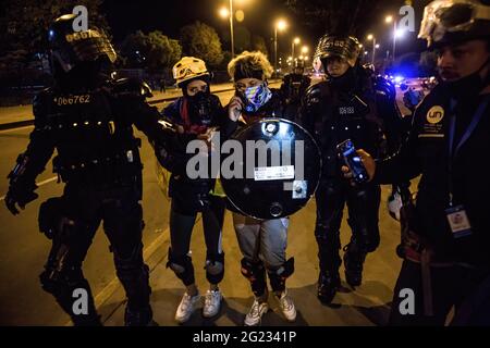 I poliziotti arrestano un protestante durante la manifestazione.il 4 giugno, il governo colombiano ha ordinato ai manifestanti di smantellare il campo medico volontario alla 'porta americana' ribattezzata 'porta di resistenza' a Bogotà. In risposta a ciò, le organizzazioni per i diritti umani hanno chiesto al sindaco di Bogotà di dare loro un'altra sede per la creazione del campo medico. Non hanno ottenuto una risposta e invece sono stati attaccati dalla polizia anti-sommossa durante la sera. I dimostranti sono stati sparati con barattoli di gas lacrimogeni, granate di stordimento e cannoni ad acqua. Il confronto durò più di quattro ore. Molte persone Foto Stock