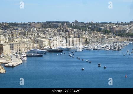 Barche di lusso ormeggiate nel porto di fronte a una splendida città portuale storica di Valetta a Malta Foto Stock