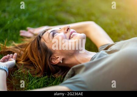 Donna spensierata sdraiata sull'erba al sole Foto Stock