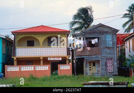 Il contrasto tra una moderna casa in cemento e una tradizionale casa in clapperboard. Belize City, America Centrale Foto Stock