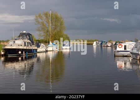 Barche ormeggiate e crociere in cabina sul fiume ANT a Ludham bridge, Norfolk Broads Foto Stock