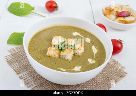 In una ciotola bianca, la zuppa di purea con spinaci e crostini. Nutrizione adeguata. Foto Stock