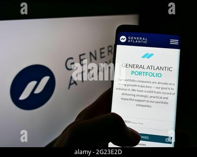 Persona che detiene il telefono cellulare con il sito web della società di private equity statunitense General Atlantic sullo schermo di fronte al logo. Mettere a fuoco il centro del display del telefono. Foto Stock
