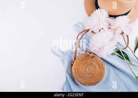 Abbigliamento estivo donna, accessori. Elegante cappello di paglia femminile, abito blu, borsa di rattan, peony Foto Stock