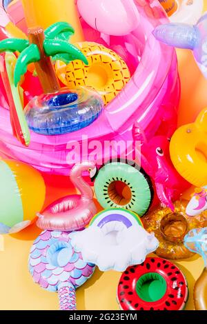 molti gonfiabili piscina di forme e colori diversi su uno sfondo giallo. immagine verticale Foto Stock