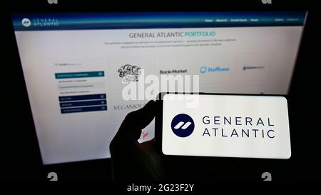 Persona che detiene smartphone con il logo della società di private equity statunitense General Atlantic sullo schermo di fronte al sito Web. Mettere a fuoco il display del telefono. Foto Stock