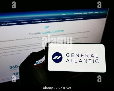 Persona che detiene smartphone con il logo della società di private equity statunitense General Atlantic sullo schermo di fronte al sito Web aziendale. Mettere a fuoco il display del telefono. Foto Stock