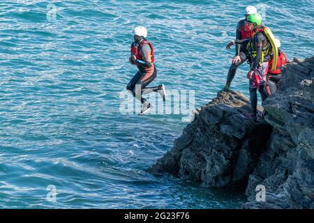 I vacanzieri saltano dalle rocce costellando con una guida su Towan Head a Newquay in Cornovaglia. Foto Stock