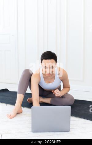 Bella donna adulta che fa sport, stretching e yoga sul tappetino a casa. Sport messi in quarantena durante il blocco del coronavirus. Foto Stock