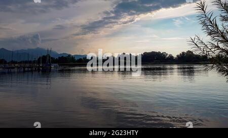 Chiemsee al tramonto vicino a Prien am Chiemsee, Baviera, Germania, porticciolo e colline alpine alla luce della sera Foto Stock