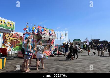I bambini che si divertano con le giostre funebri su Hastings Pier, Hastings, East Sussex, UK Foto Stock