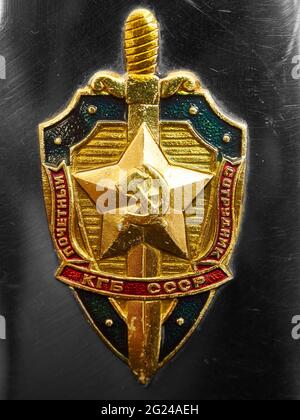 Immagine rappresentativa del badge/insegne dell'agenzia di sicurezza KGB, attaccata ad un matraccio di metallo (proprio del fotografo) - sfondo metallico. Foto Stock