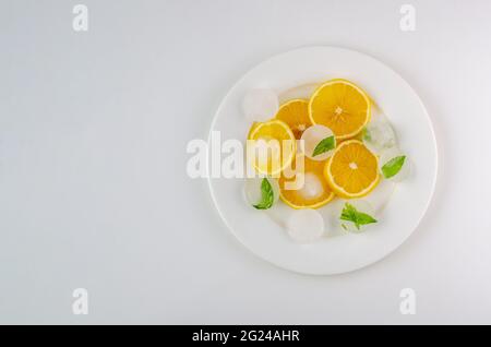 Limoni affettato con ghiaccio su un piatto bianco con fondo bianco Foto Stock