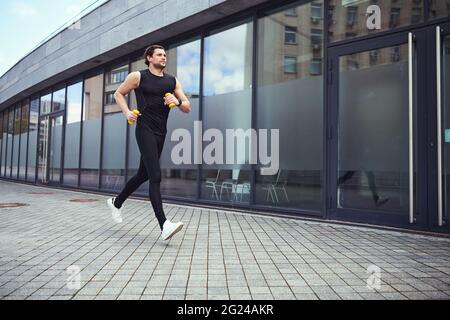 Giovane uomo attivo che corre per strada Foto Stock