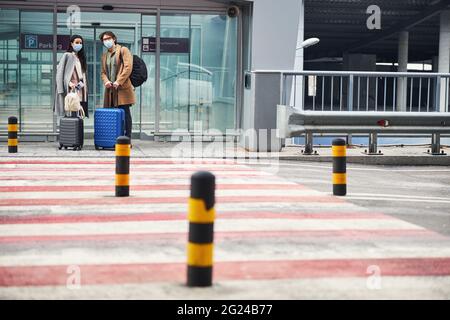 Giovane coppia in maschere mediali in piedi da attraversamento pedonale Foto Stock
