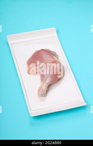 Coscia di pollo intera grezza senza pelle sistemata a forma rettangolare piatti con fondo di colore pieno blu ghiaccio Foto Stock