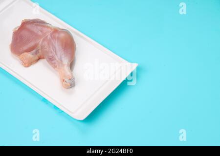 Coscia di pollo intera grezza senza pelle sistemata a forma rettangolare piatti con fondo di colore pieno blu ghiaccio Foto Stock