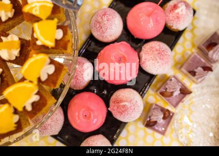 mele in caramello rosa su un piatto nero su un tavolo a buffet Foto Stock