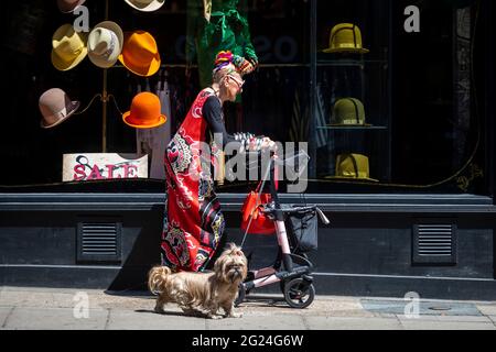 Londra, Regno Unito. 8 giugno 2021. UK Weather - una donna elegantemente vestita cammina il suo cane passando un negozio di cappelli vicino a Cambridge Circus in un pomeriggio caldo e soleggiato, quando le temperature sono salite a 25C nella capitale. Credit: Stephen Chung / Alamy Live News Foto Stock