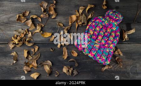 cappelli di lana lavorati a mano su rustico sfondo di legno e foglie d'autunno Foto Stock