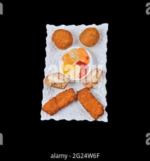 Crocchette o croquetas spagnole tradizionali fatte in casa su un piatto bianco. Cibo tapas, sfondo nero Foto Stock