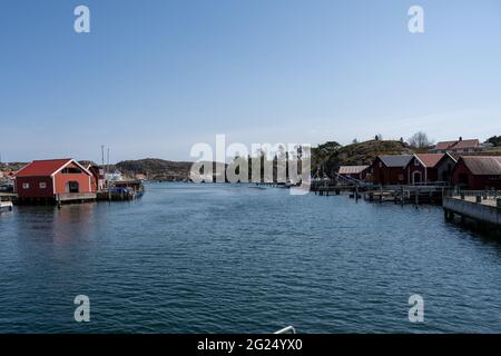 17 aprile 2021 - Hamburgsund, Svezia: Un pittoresco villaggio di pescatori sulla costa occidentale svedese. Tradizionali capanne di mare rosso e un cielo blu sullo sfondo Foto Stock