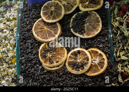 Fette di limone essiccate su foglie di tè nero con fiori di camomilla essiccati Foto Stock