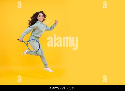 felice salto energico bambino con racchetta da tennis che corre al successo, copy space, vendita shopping sportivo. Foto Stock