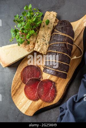 Bresaola affumicata intera e tagliata su un tagliere. Antipasti italiani Foto Stock