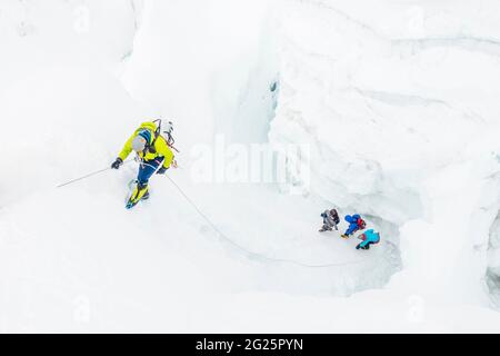 Un alpinista è sul rappel mentre la squadra sotto naviga i crepacci Foto Stock