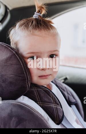 Bambino di 5 anni in un seggiolino di sicurezza per bambini seduto pazientemente nella parte posteriore di un'auto Foto Stock