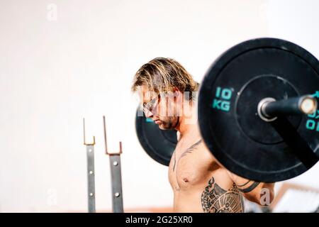 L'atleta biondo fa squats con i manubri Foto Stock