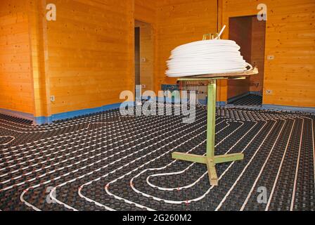 Sistema di riscaldamento a pavimento ad anello chiuso Hydronic su pannello coibentato stampato in EPS con tavolo a bobina all'interno di una casa in legno parzialmente costruita Foto Stock